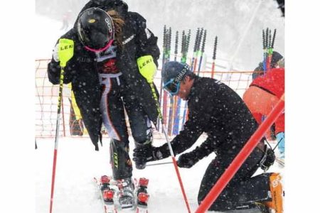 A person helps another on a snowboard